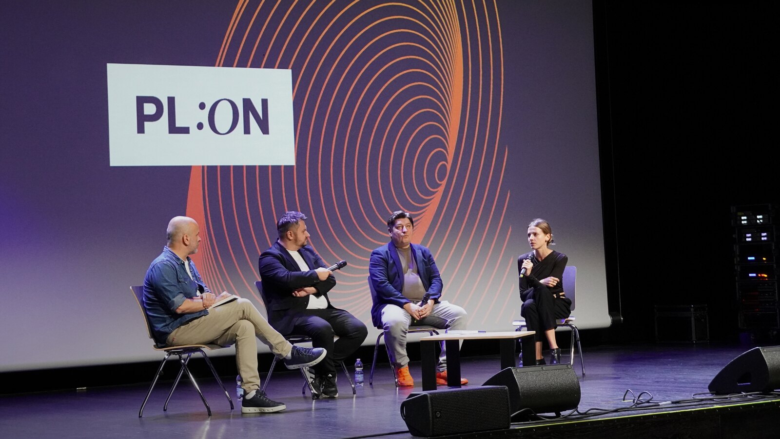 Panel dyskusyjny PL:ON — czworo rozmówców na scenie przed ekranem z key-visualem PL:ON.